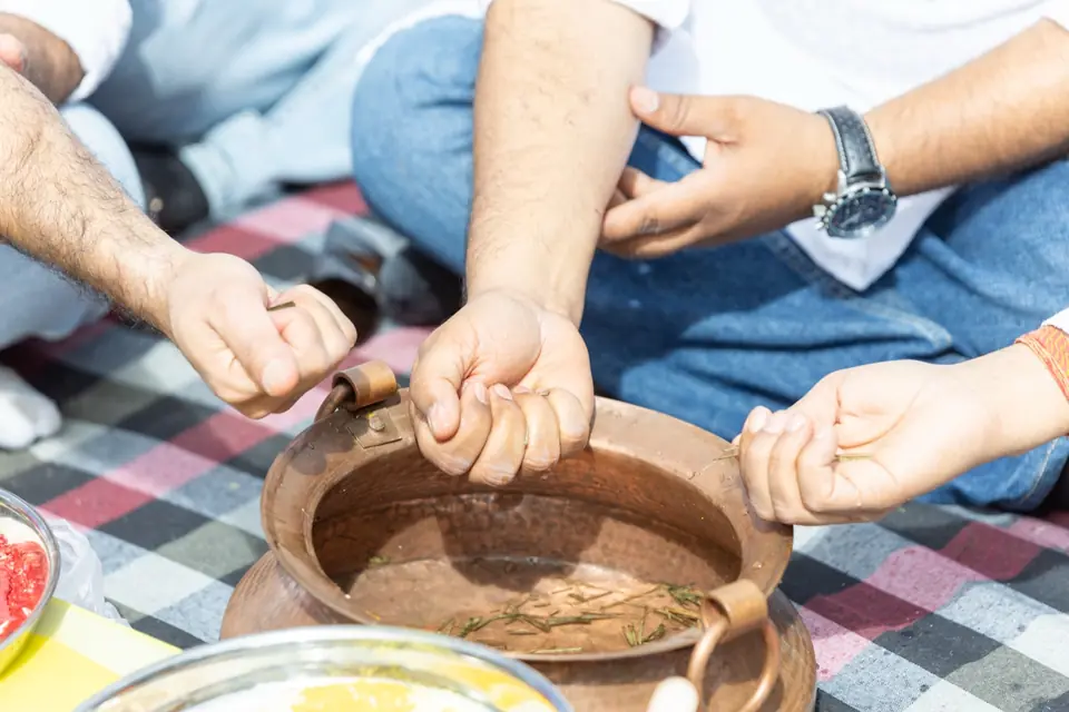 Hands held over a copper pot of water during the pooja