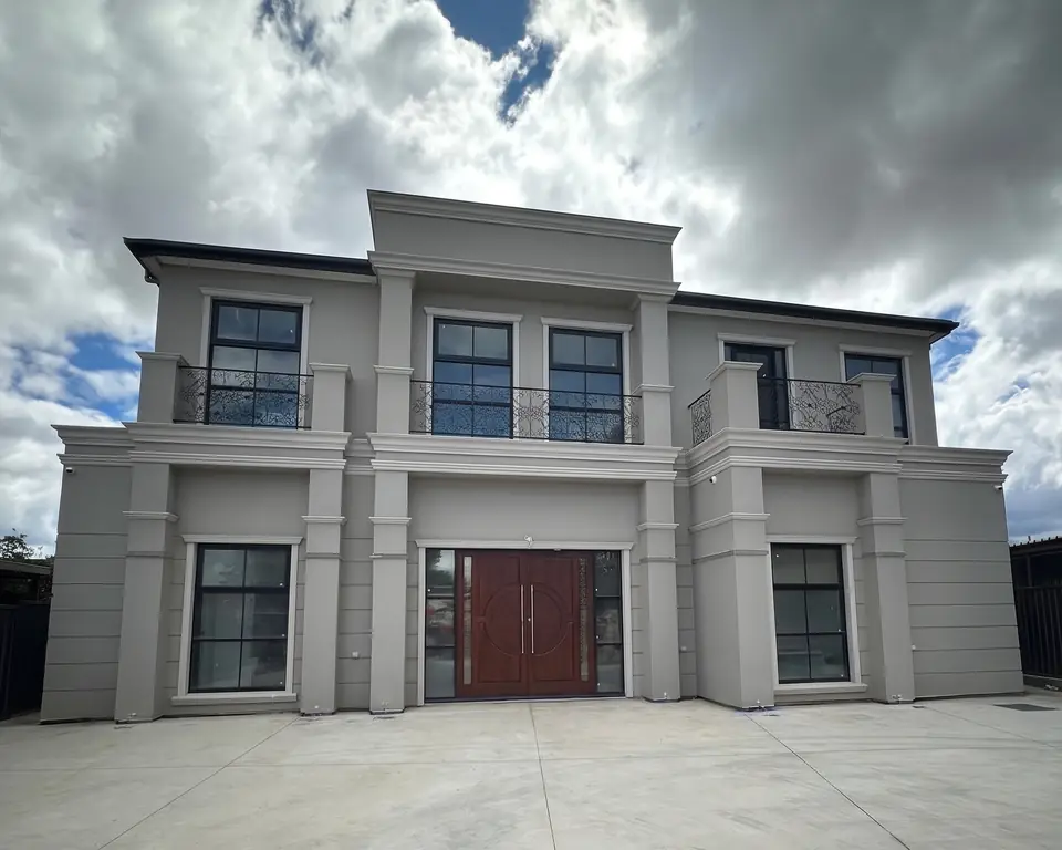 The finished two-storey temple on Peat Avenue, with timber front doors and iron balconies, under a cloudy sky