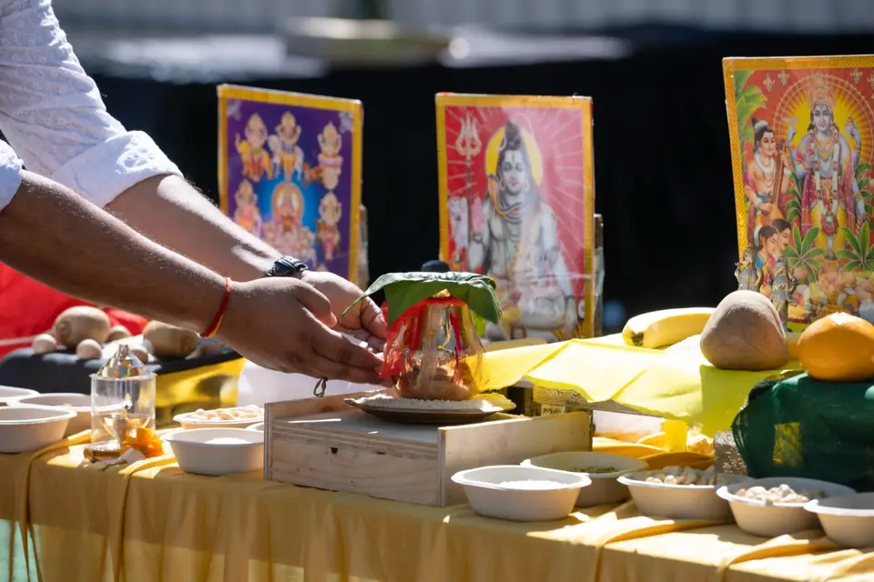 Hands placing a kalash with mango leaves on the altar